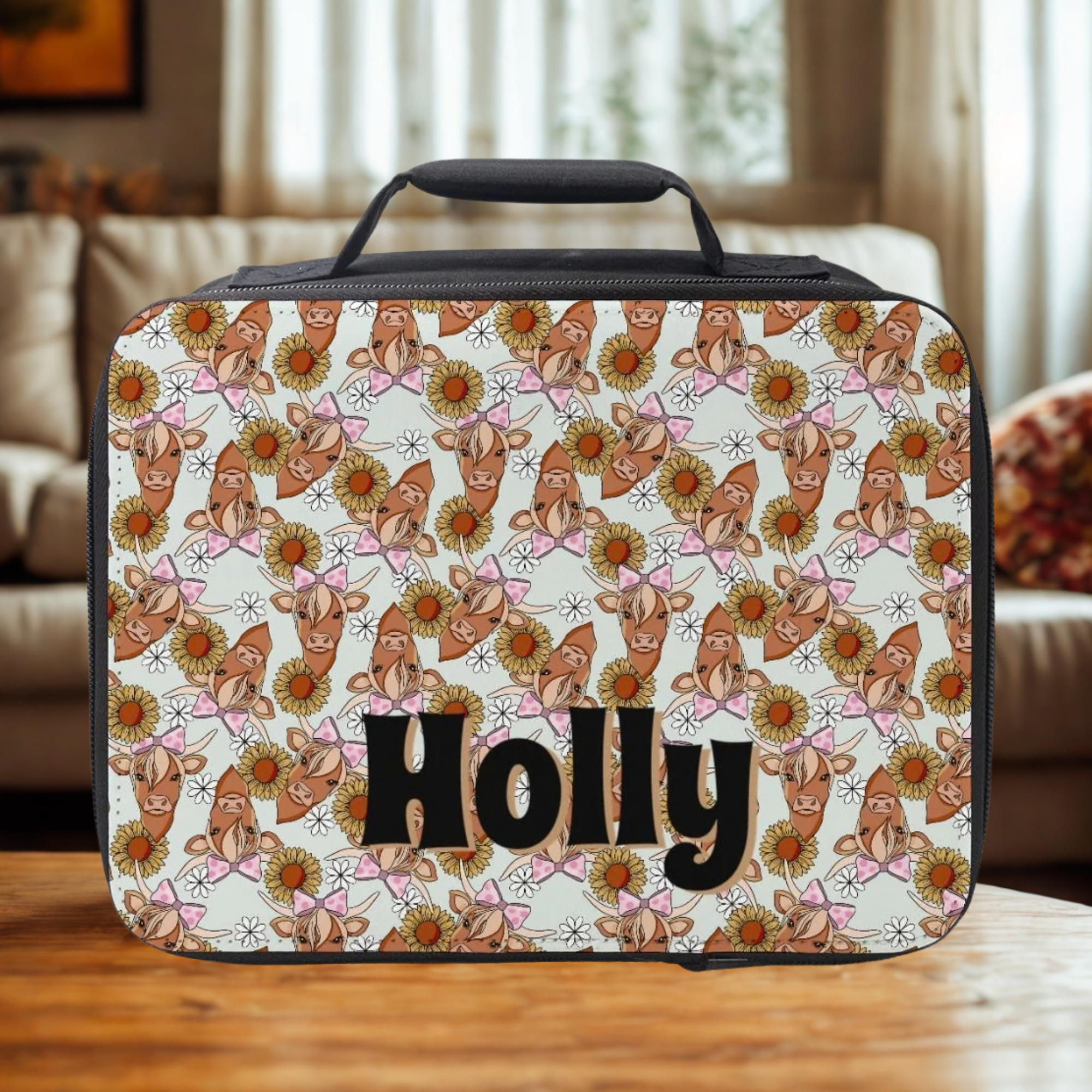  insulated lunch bag with cow pattern and 'Holly' text on a wooden surface