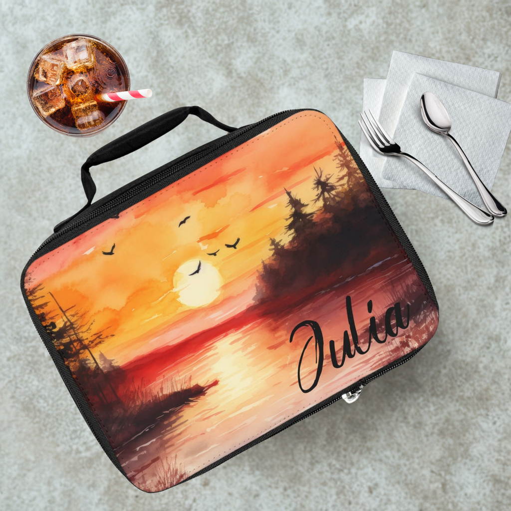 Lunch bag with sunset design and 'Julia' branding on a cafeteria table with a drink and utensils.