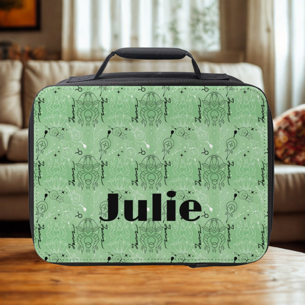 lunch bag with green & black Taurus zodiac patter and 'Julie' printed on it, placed on a wooden living room table.