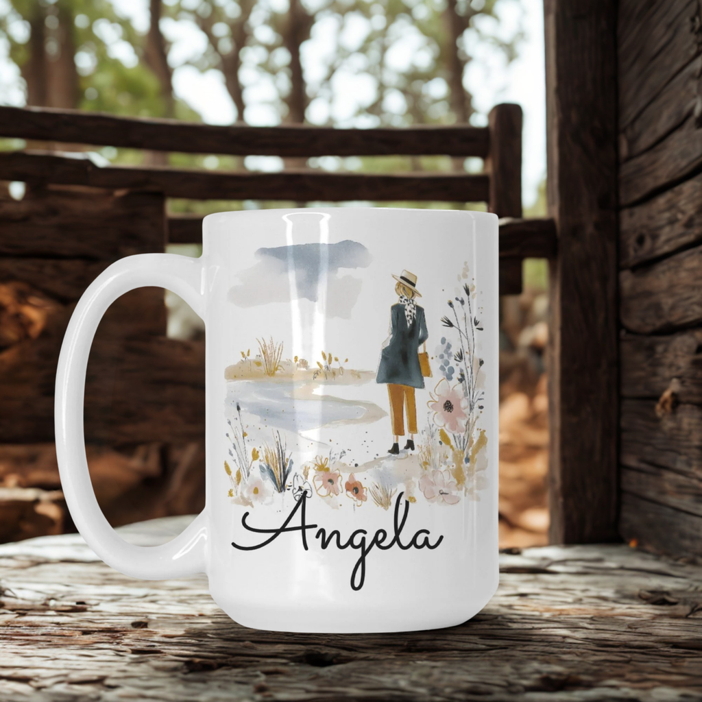 White mug with a design and the name 'Angela' on a wooden surface with a blurred natural background