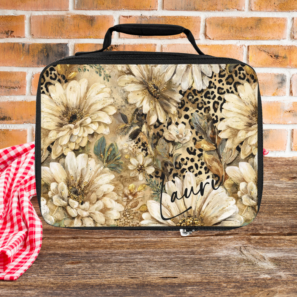 Floral and leopard print patterned bag with 'Laurie' custom name on a wooden picnic table against a brick wall background.