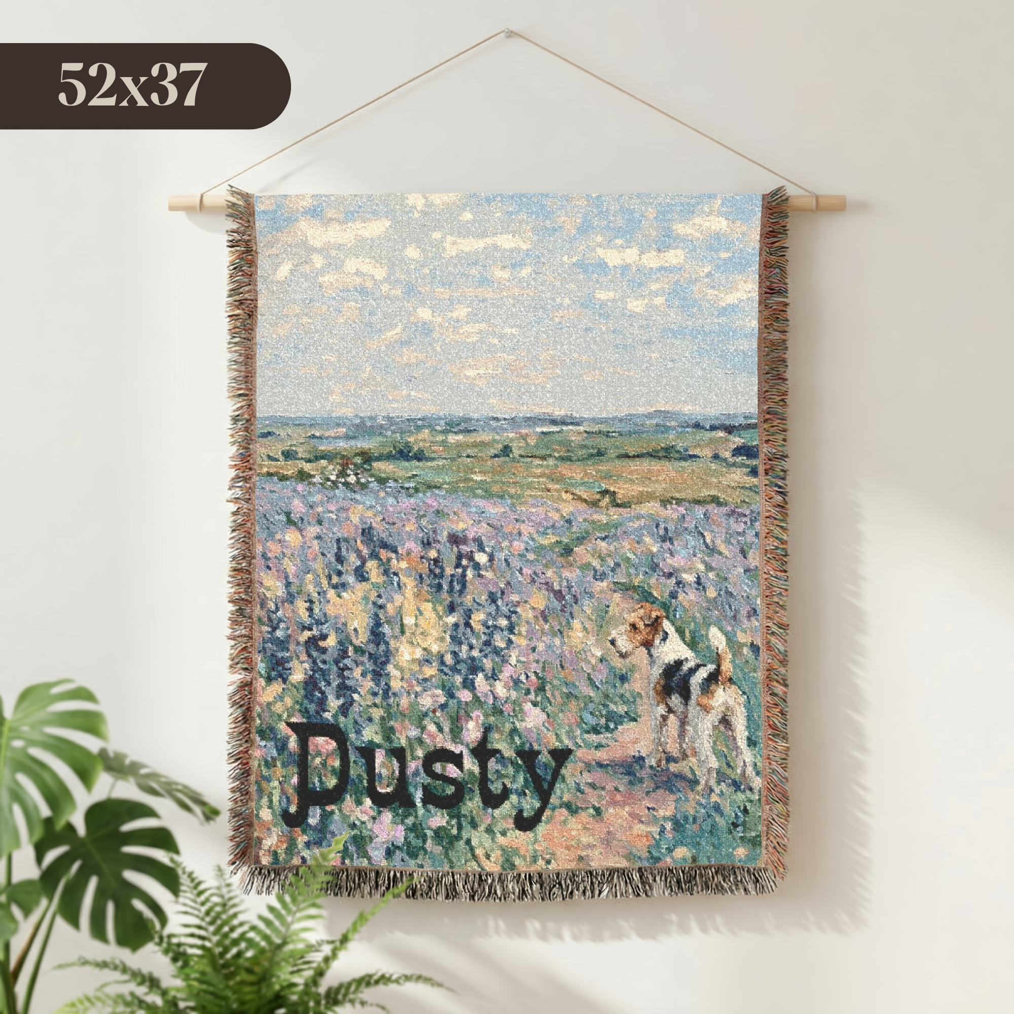 A woven wall tapestry featuring an impressionistic lavender field landscape with a dog and the name 'Dusty' in script, hanging on a light wall with a plant visible at the lower left.