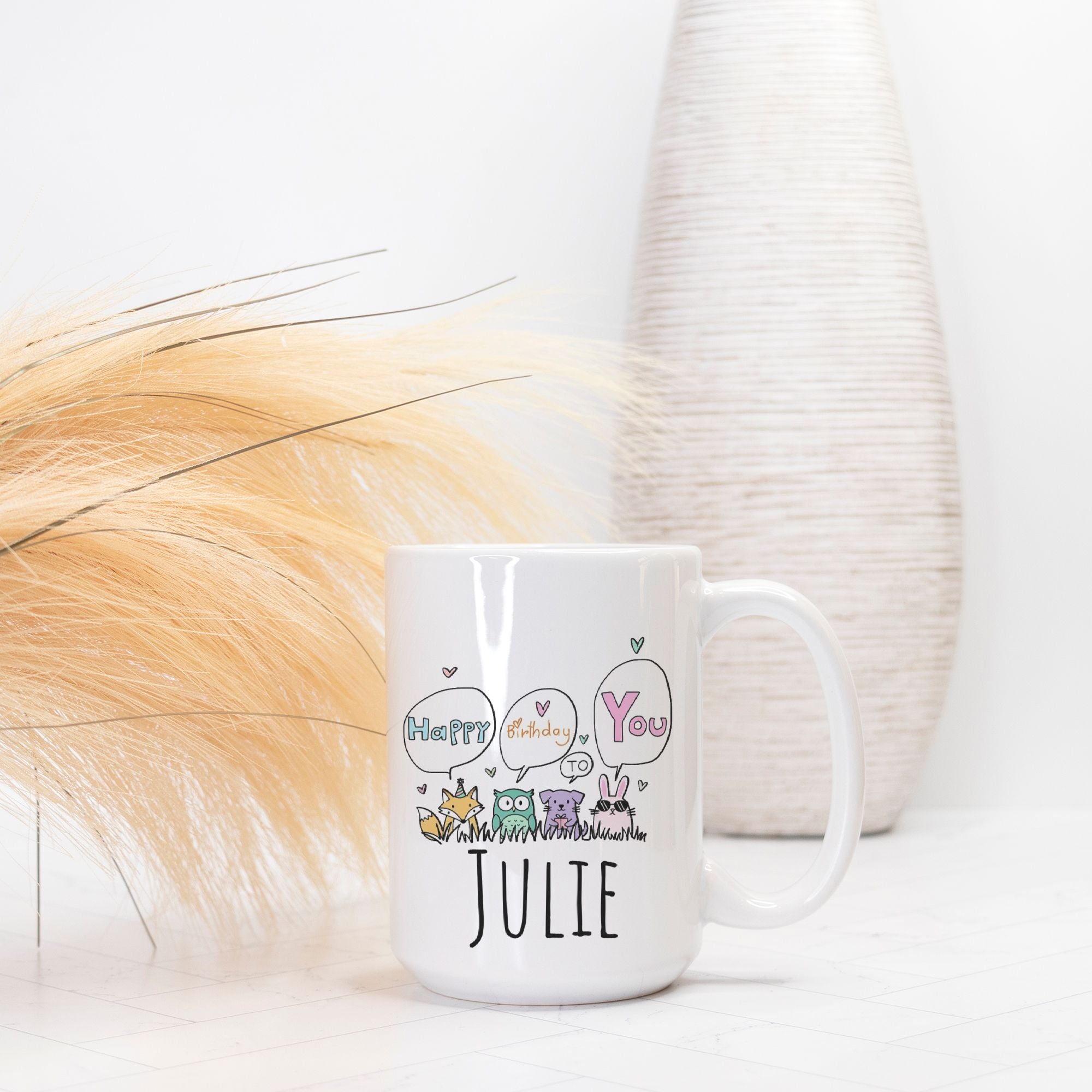 White mug with decorative text and baby animal illustrations on a light background