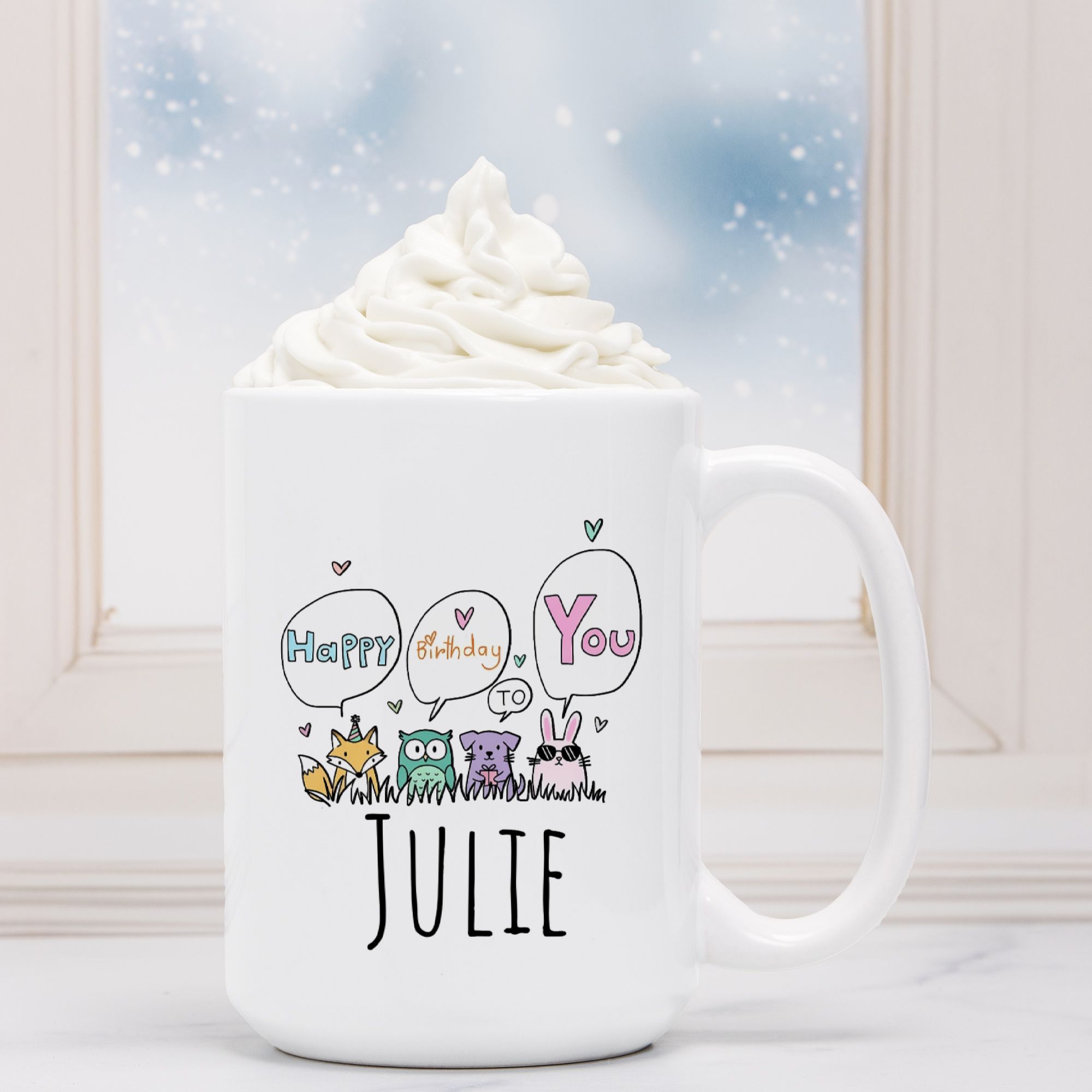 White mug with cartoon owls and text 'Happy Birthday to Julie' against a snowy window background.