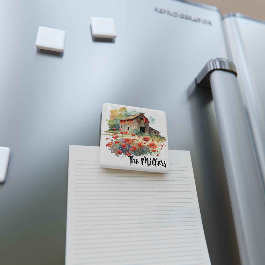 Fridge magnet with a house and flowers design on a refrigerator next to a notepad.
