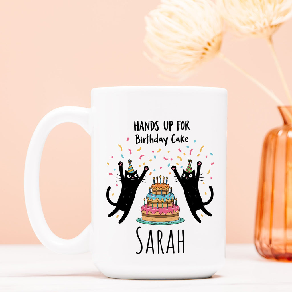 White mug with black cats and birthday cake design on a pink background