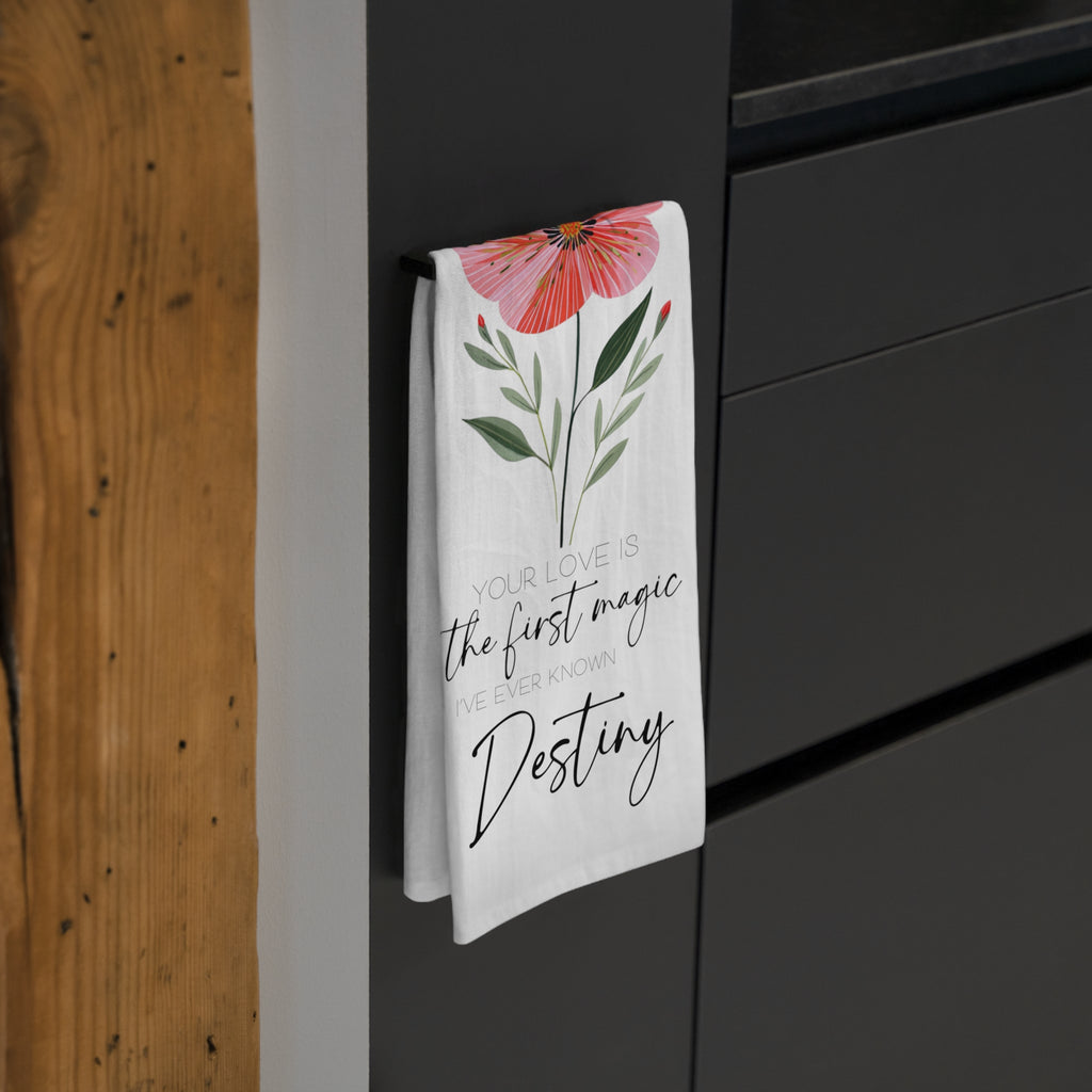 Floral tea towel with custom text hanging on a black cabinet.