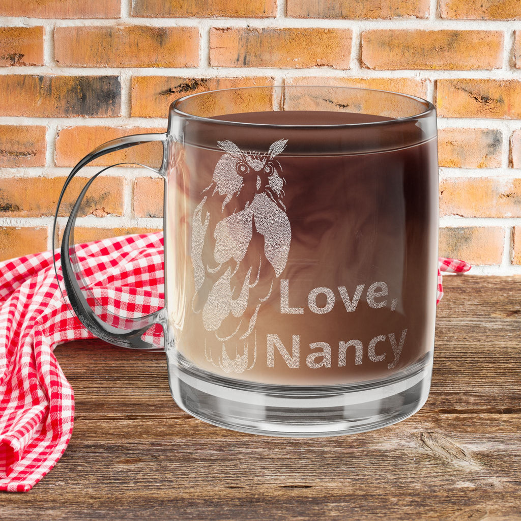 12oz round glass mug with an owl design and custom text on a picnic table with a brick background.