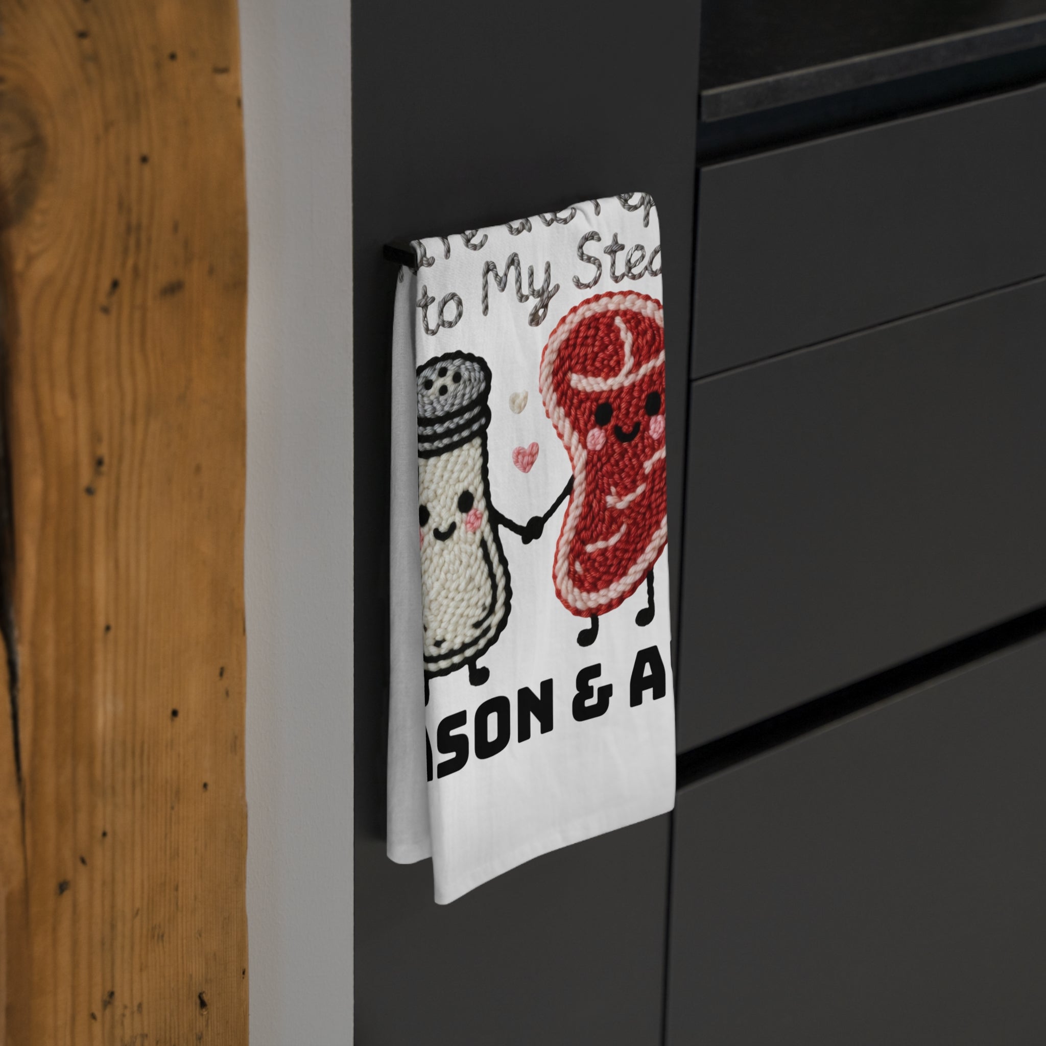 Towel with cartoon salt and pepper shakers and a steak on a black surface.