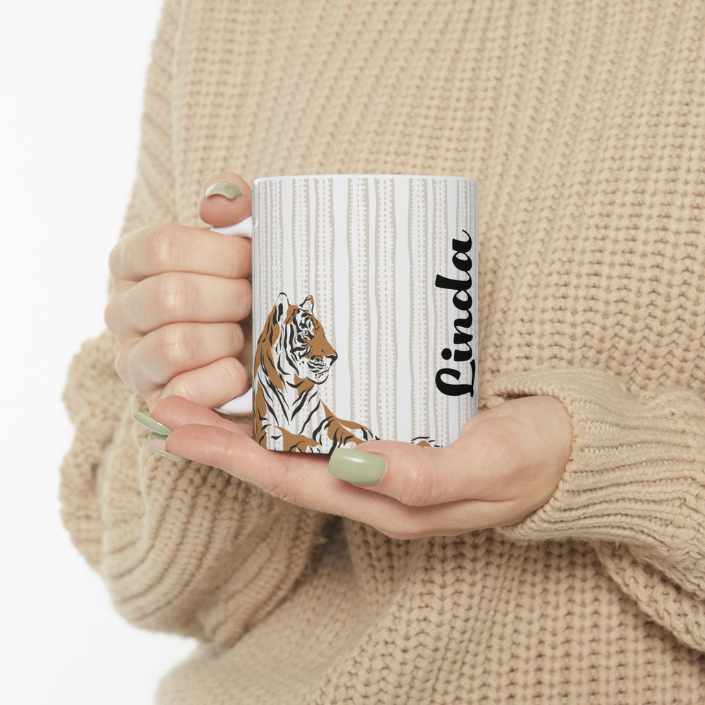 Person holding a 11oz mug with a tiger design and the name 'Linda' on it.