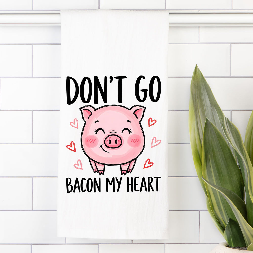 Tea Towel with Cartoon pig with text 'Don't go bacon my heart' on a white tiled wall.