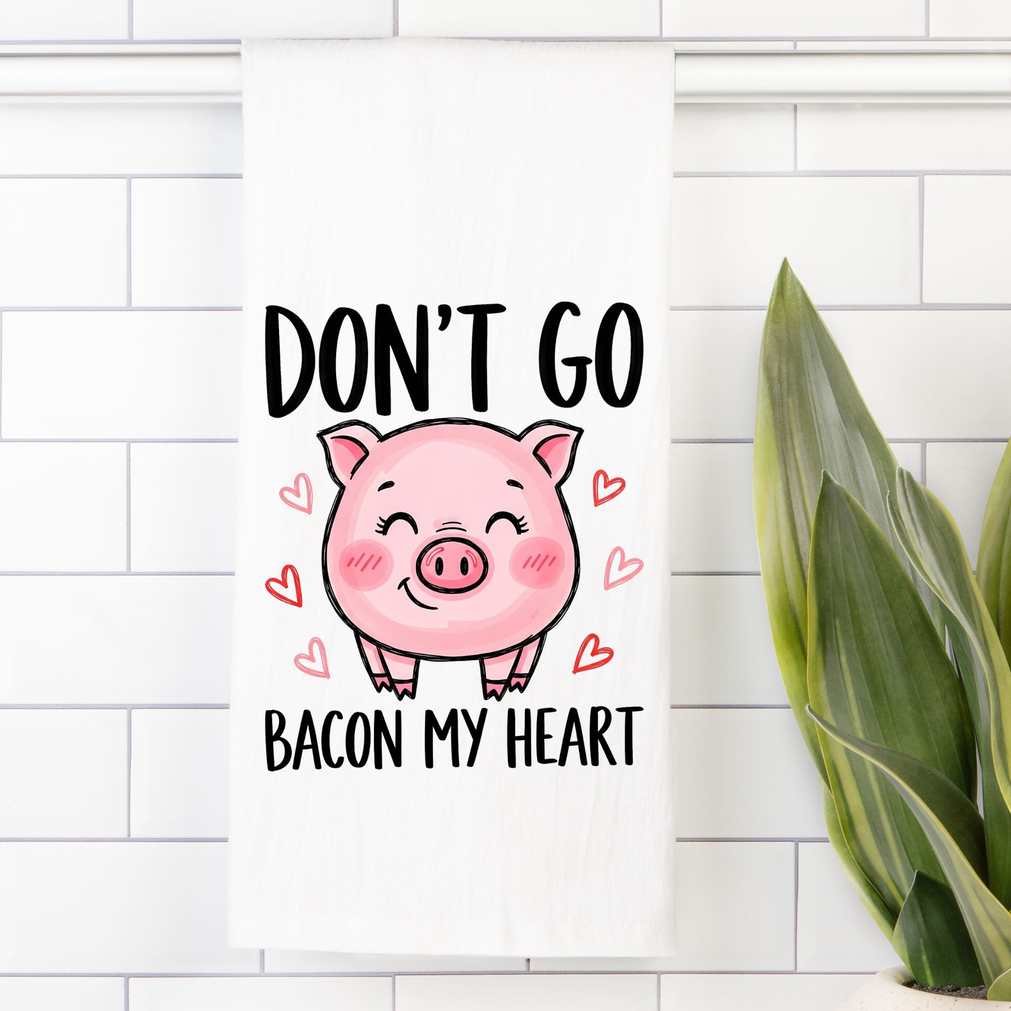 Tea Towel with Cartoon pig with text 'Don't go bacon my heart' on a white tiled wall.