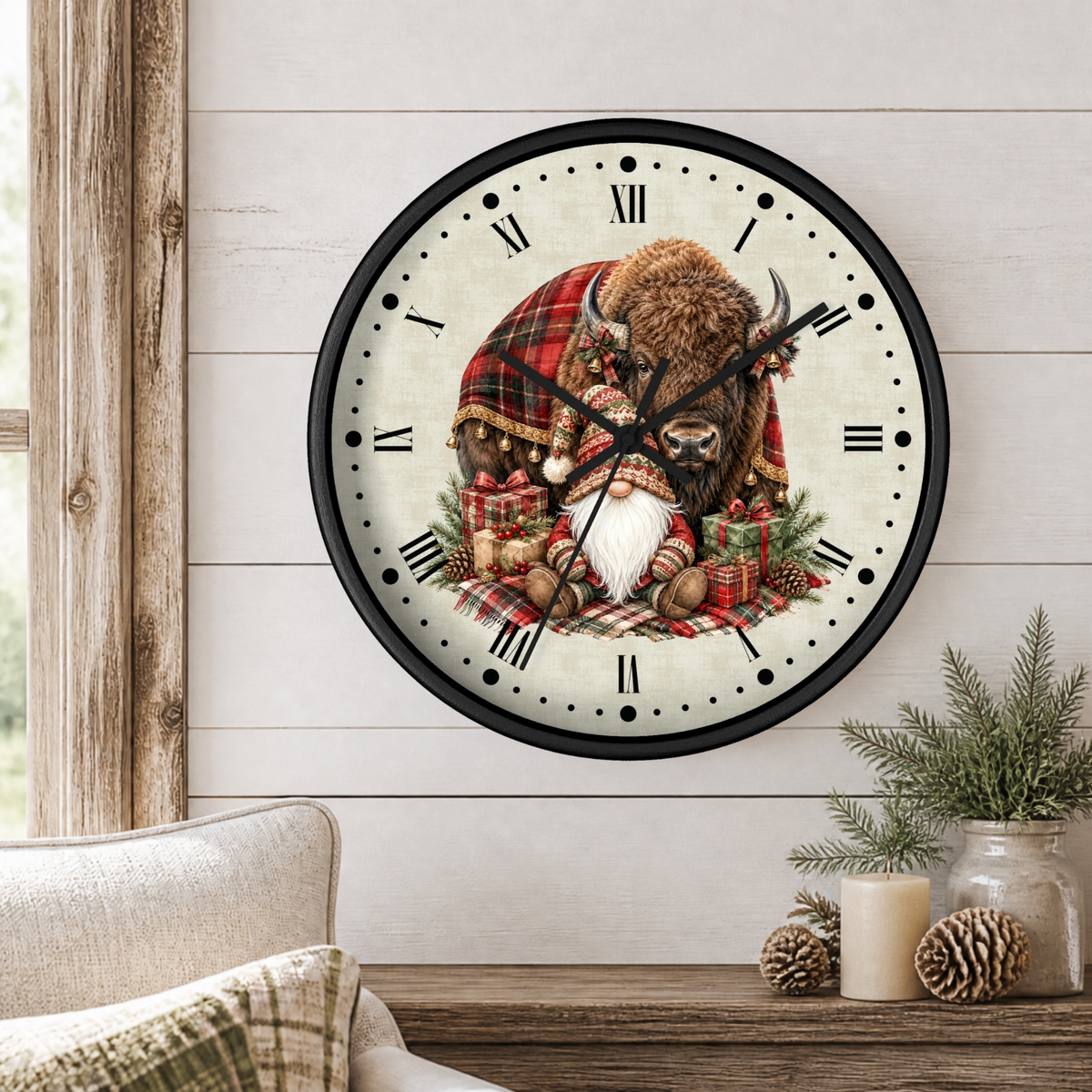 A round wall clock with a black frame and Roman numerals, featuring a festive bison illustration wrapped in a red plaid blanket with a white bearded gnome, styled on a white wood paneled wall above a rustic table with candles and pine branches.