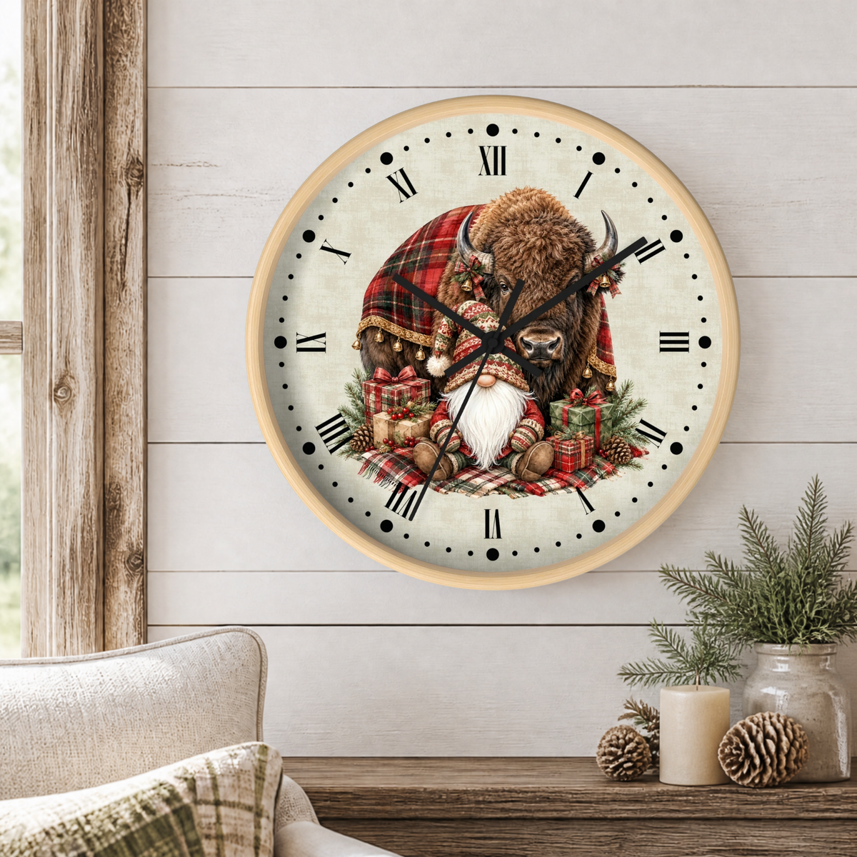 A round wall clock with a rustic wood frame hangs on a white shiplap wall above a wooden table. The clock face features an illustration of a bison wearing a red plaid winter coat and hat, with a bearded gnome, surrounded by pinecones and gifts.