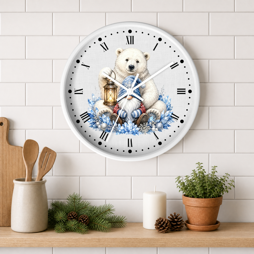A round wall clock with a white face and black Roman numerals, featuring an illustration of a polar bear holding a lantern surrounded by blue snowflakes and winter elements. The clock is mounted on a white subway tile wall above a wooden shelf styled with kitchen utensils, pine branches, a candle, and a potted plant.