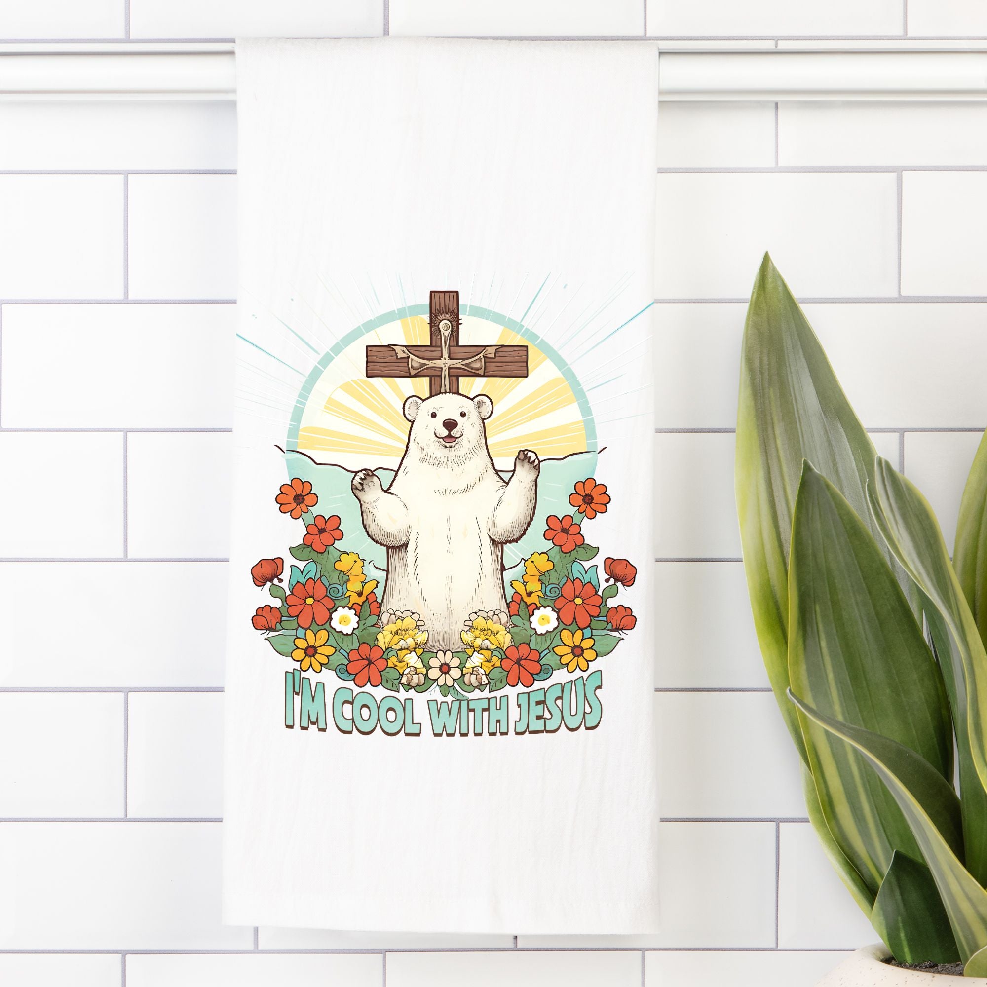 White tea towel with a bear in front of a cross, flowers, and 'I'm cool with Jesus' text on a white tiled wall.