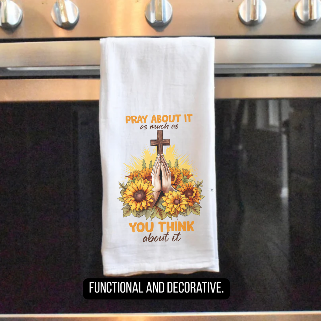 Decorative tea towel with cross and sunflower design hanging on a stove.
