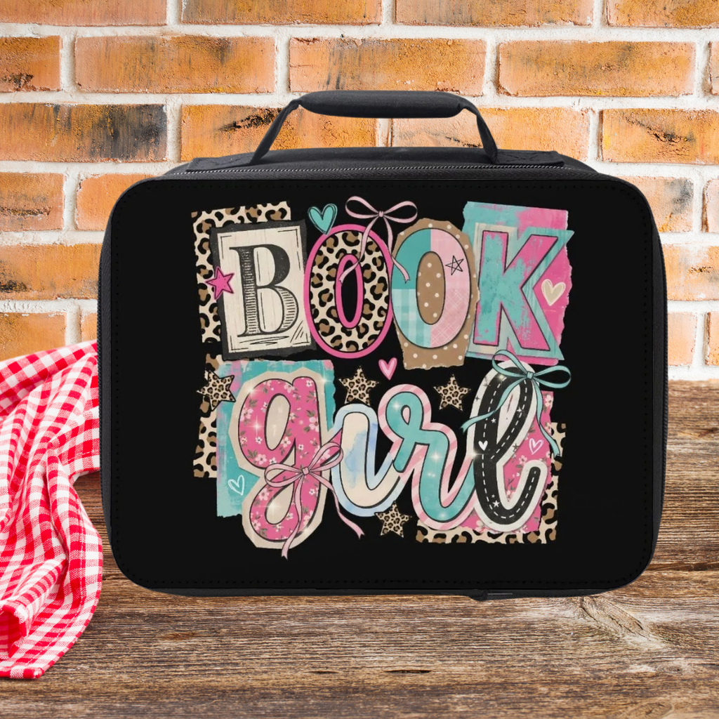 Black lunch bag with 'Book Girl' design on a wooden picnic table against a brick wall background