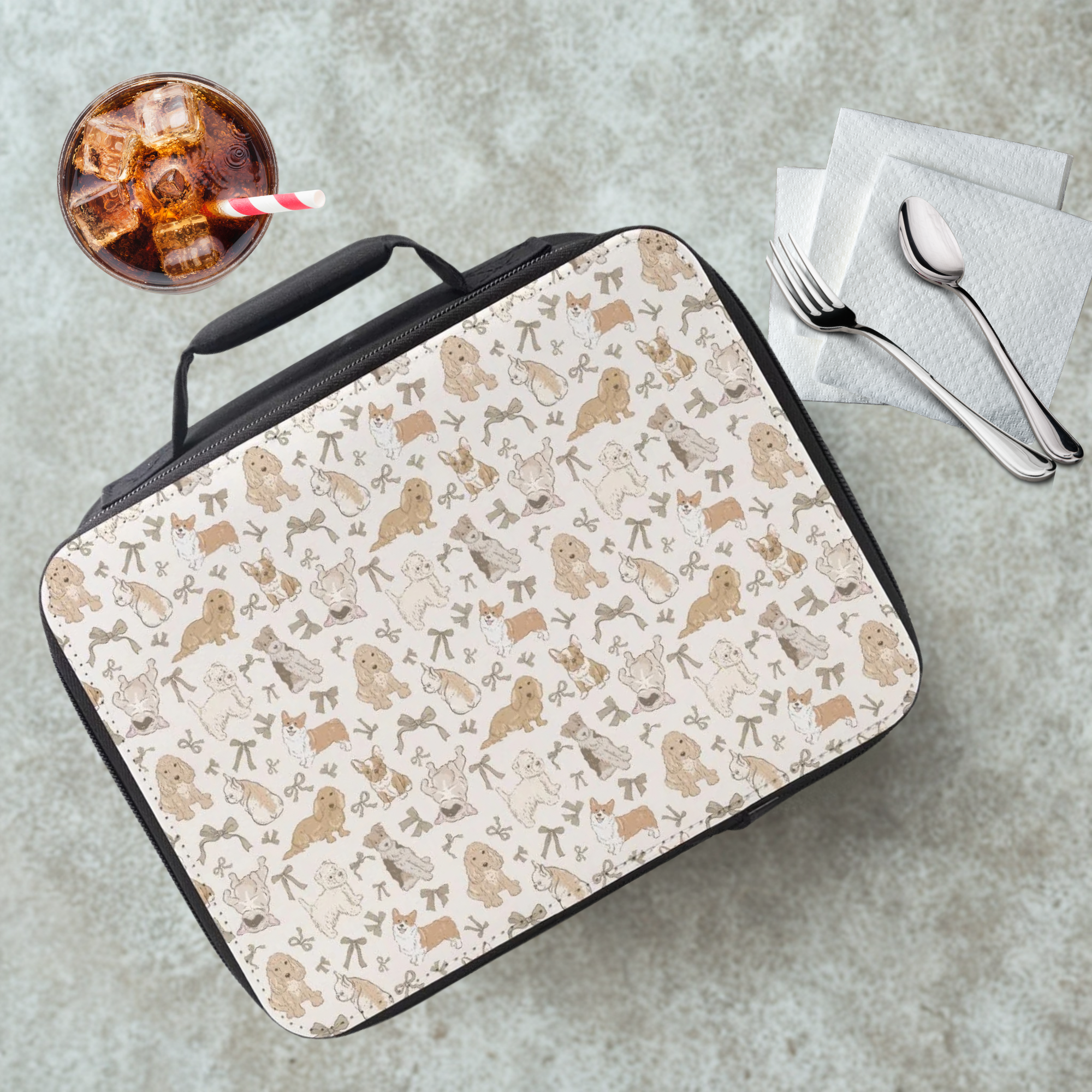 Lunch bag with dog pattern on a cafeteria table with a drink and utensils.