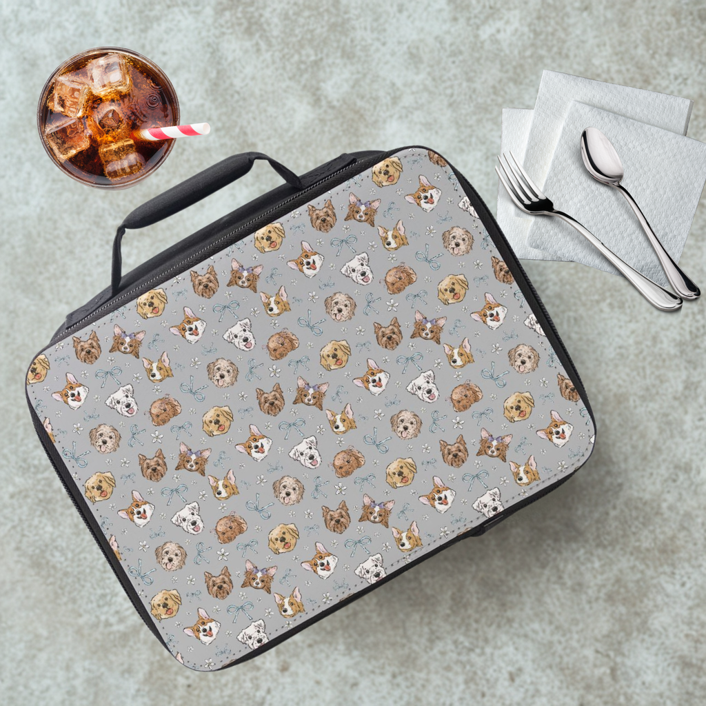 Lunch bag with dog pattern on a concrete surface with a drink and utensils.
