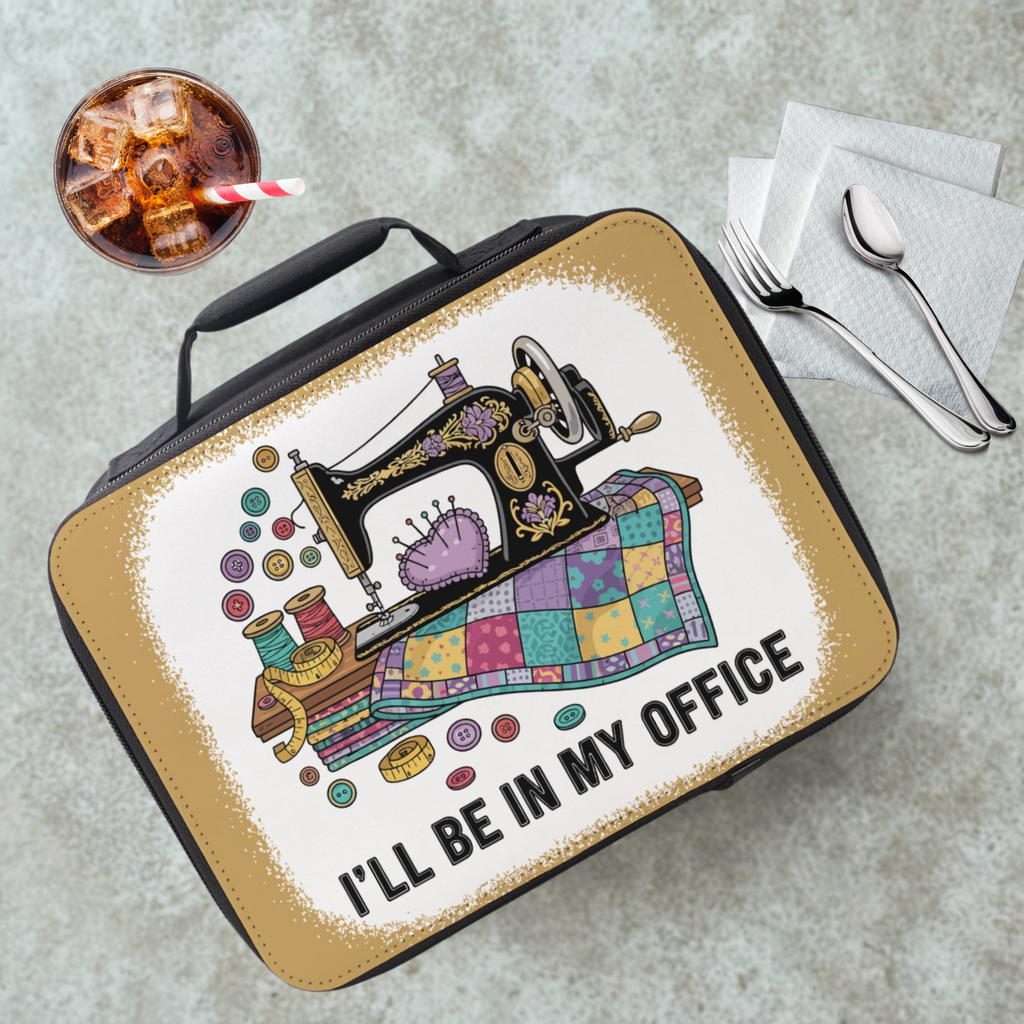 Lunch box with sewing machine design and text 'I'll be in my office' on a concrete surface.
