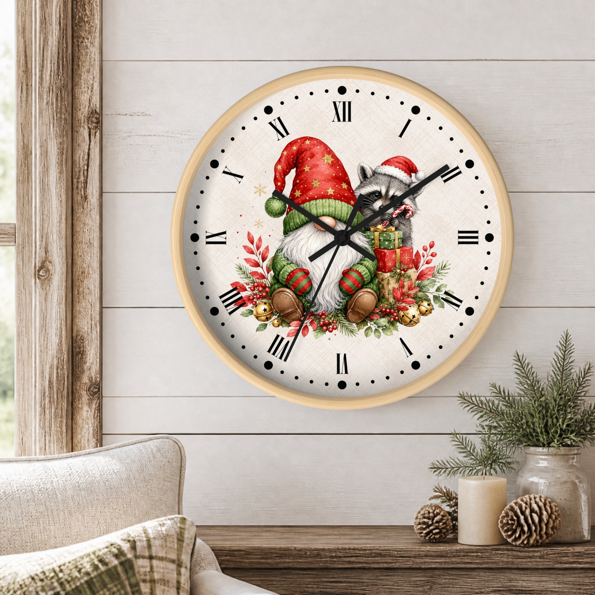A round wall clock with a light wood frame and a white face, featuring a festive Christmas gnome illustration with a red Santa hat, beard, gift box, acorns, and green foliage. The clock is mounted on a white shiplap wall above a wooden table with pine branches and candles.