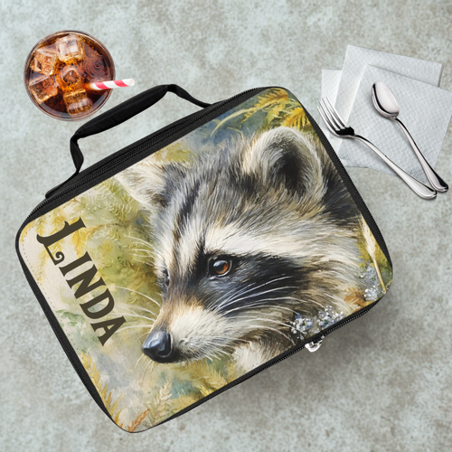 Lunch bag with raccoon design and 'LINDA' text on a table with a drink and utensils.