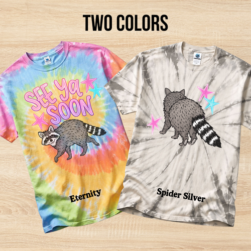 Two tie-dye t-shirts with raccoon designs and color names on a wooden surface.