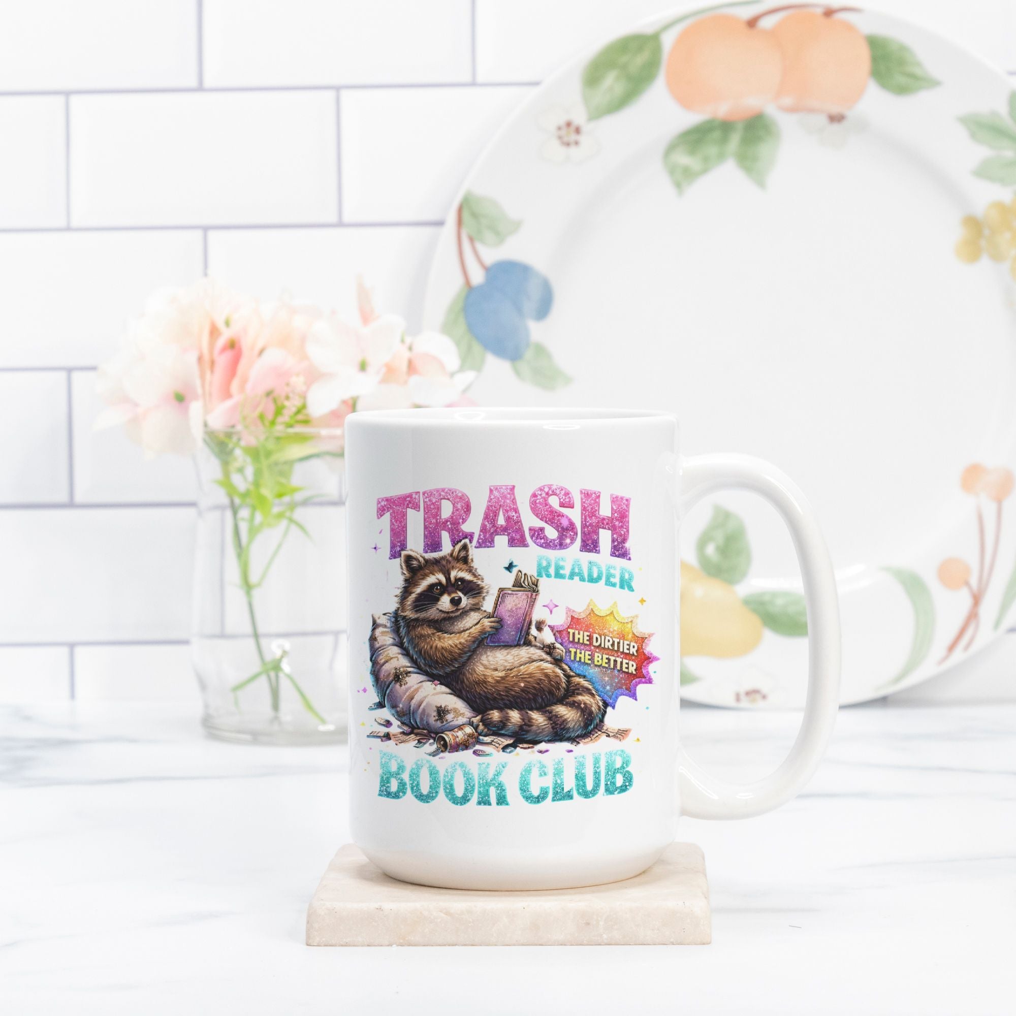 Mug with a raccoon illustration and text 'Trash Reader Book Club' on a kitchen counter.