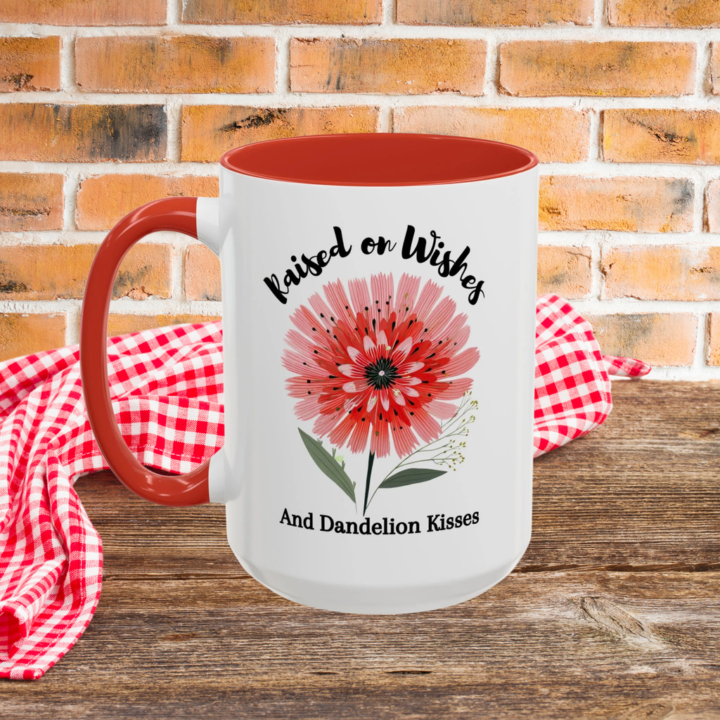 Mug with red interior, handle, floral design, and text on a wooden picnic table with a brick wall background.