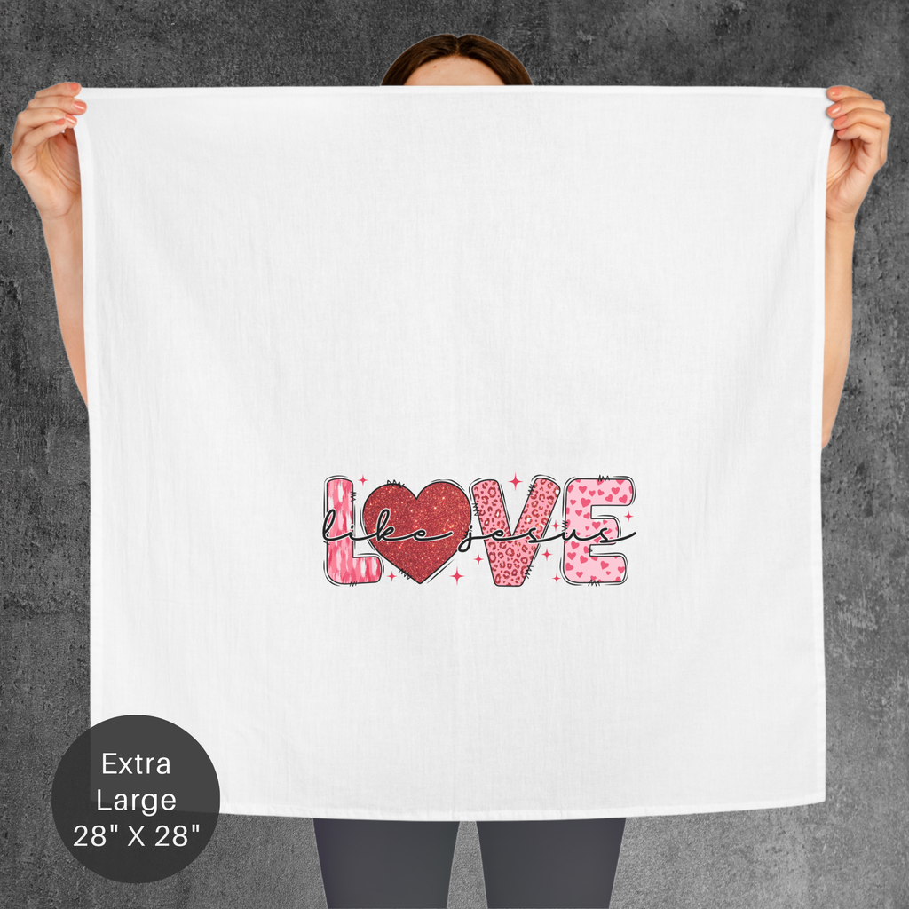 Person holding an extra large white tea towel with 'LOVE Like Jesus' printed on it against a gray background