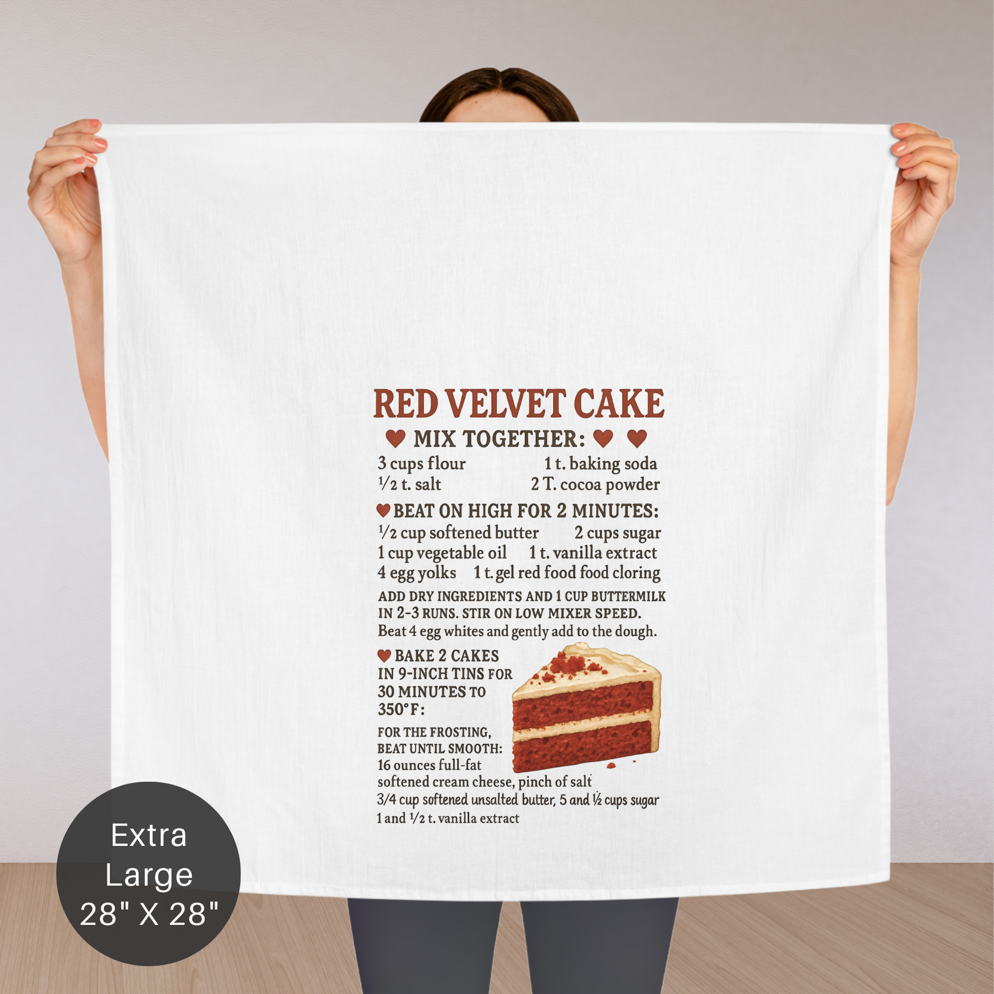 Person holding an extra large tea towel with a  Red Velvet Cake recipe with a slice of cake illustration.