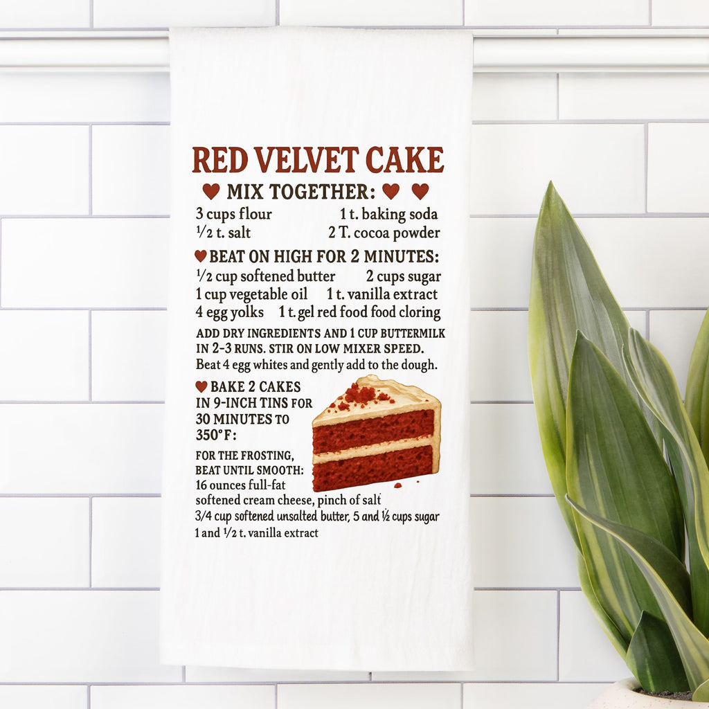 Tea towel with a  Red velvet cake recipe on a tiled wall with a plant in the corner