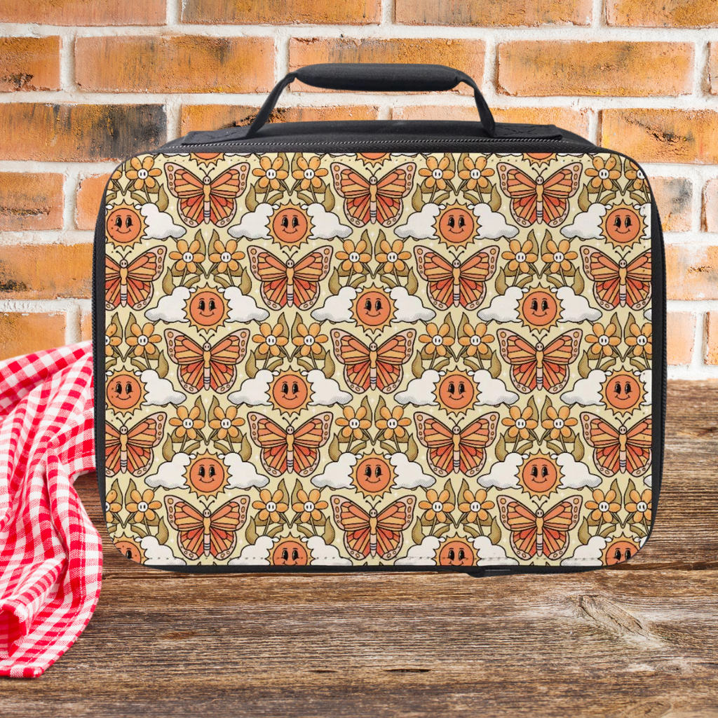 Lunch bag with butterfly and flower pattern on a wooden picnic table against a brick wall background