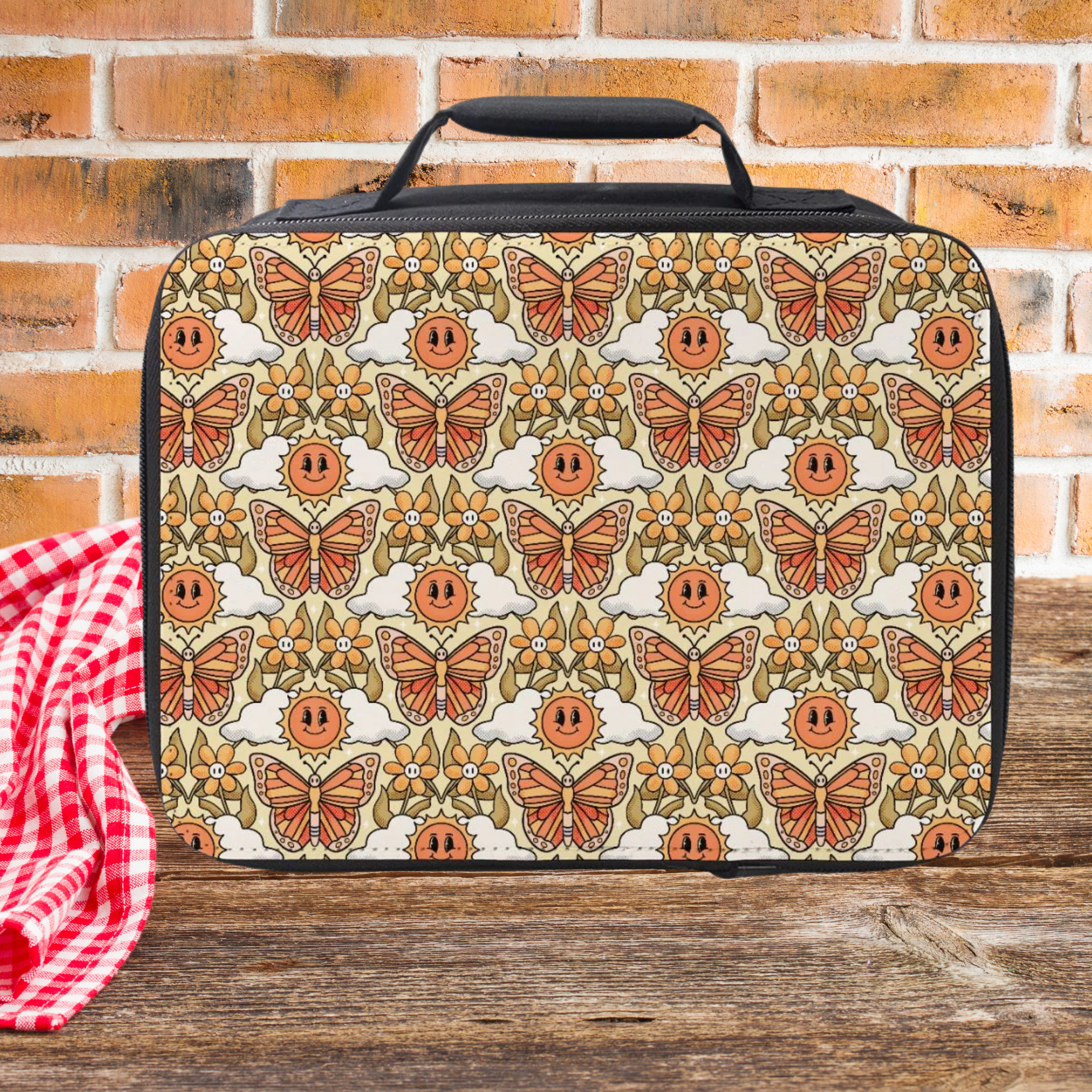 Lunch bag with butterfly and flower pattern on a wooden picnic table against a brick wall background