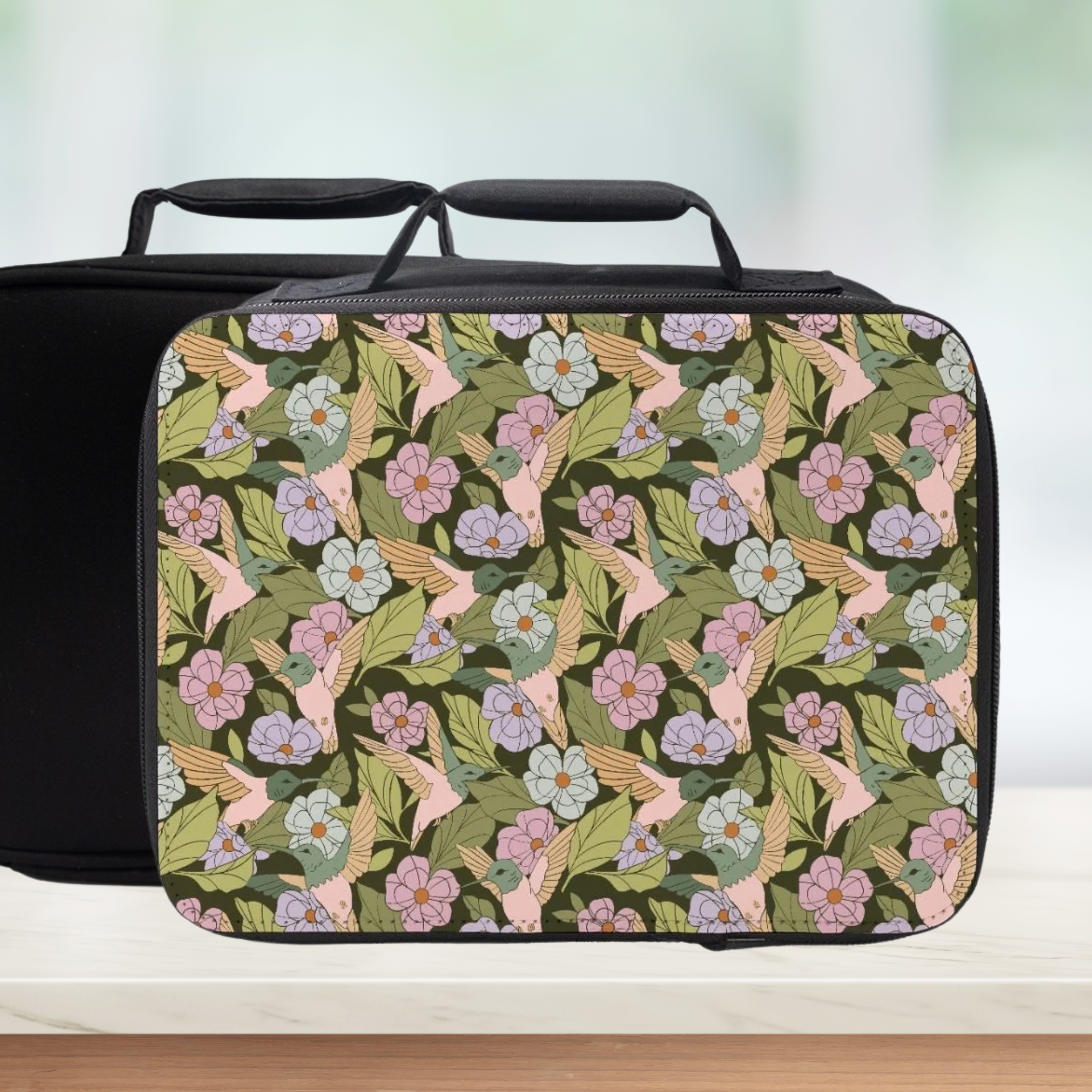 Floral and hummingbird patterned lunch bag on a white surface with a blurred background