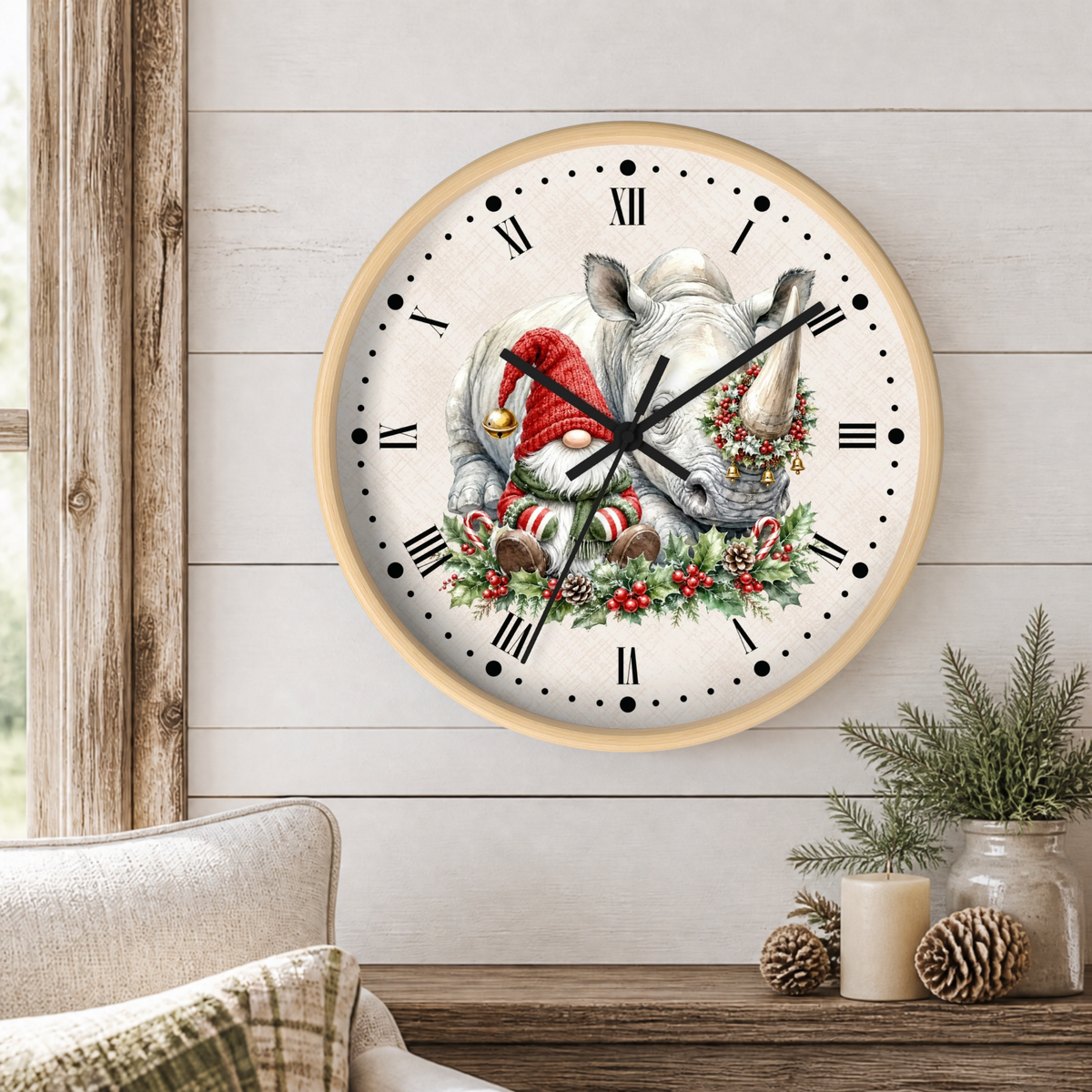 A round wall clock with a light wood frame hangs on a white shiplap wall above a wooden table. The clock face features a festive illustration of a rhinoceros wearing a red Santa hat and wreath, surrounded by candy canes and holly.