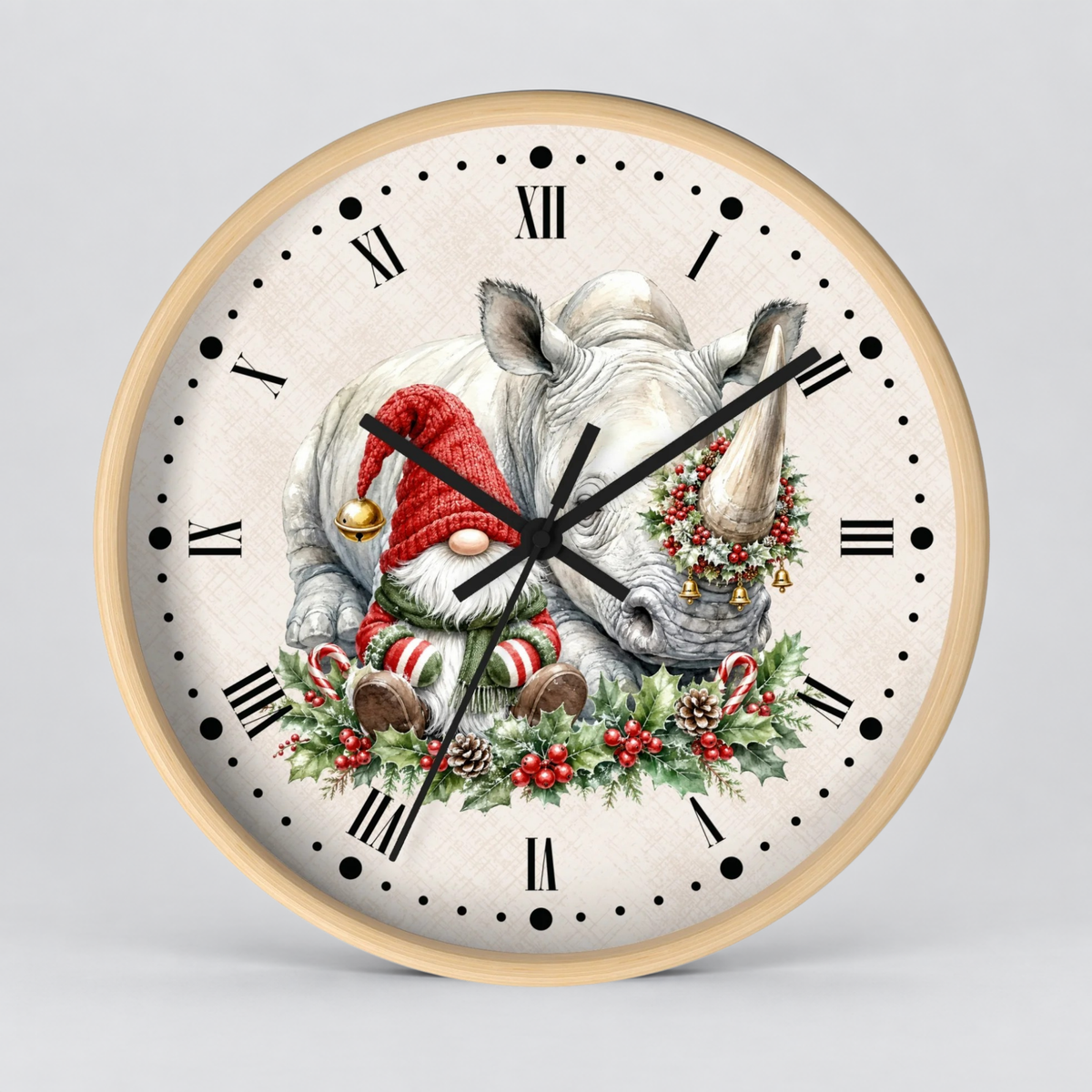 A round wall clock with a light wood frame and a cream-colored face, featuring a festive illustration of a white rhinoceros wearing a red Santa hat and a green holiday wreath, with black Roman numerals and hands on a light gray background.