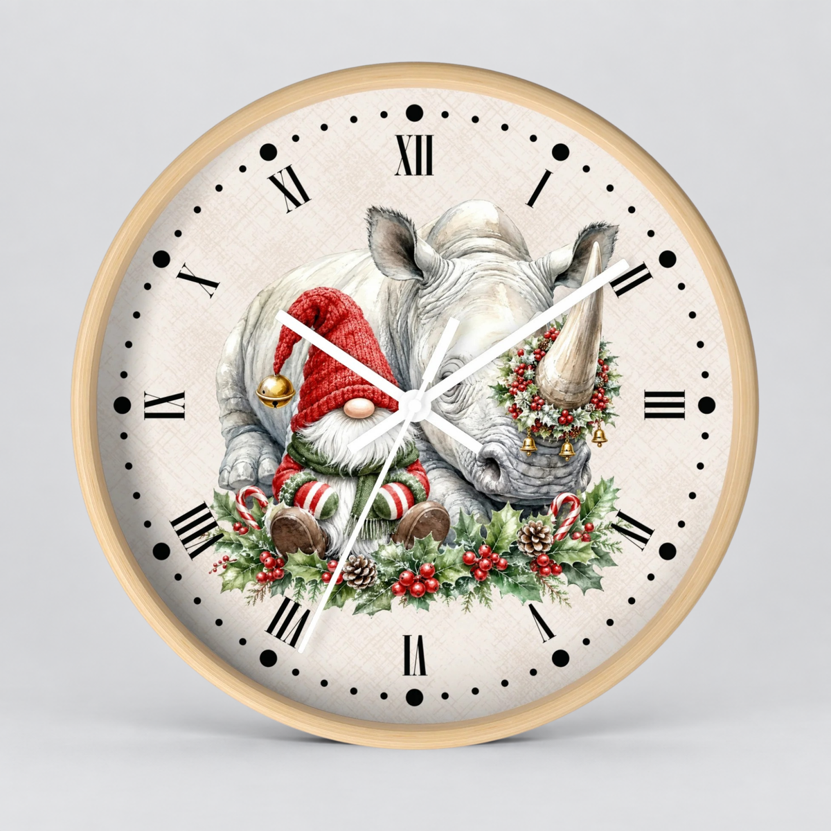 A round wall clock with a light wood frame and a cream-colored face featuring a whimsical illustration of a white rhinoceros wearing a red Santa hat and green holiday wreath, with black Roman numerals and white hands.