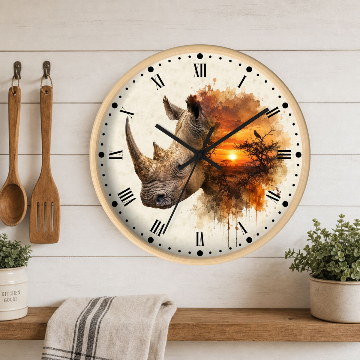 A round wall clock with a light wood frame hangs on a white wood-paneled wall above a shelf. The clock face features a watercolor-style illustration of a rhinoceros in warm earth tones against an orange sunset, with black Roman numerals and hands.