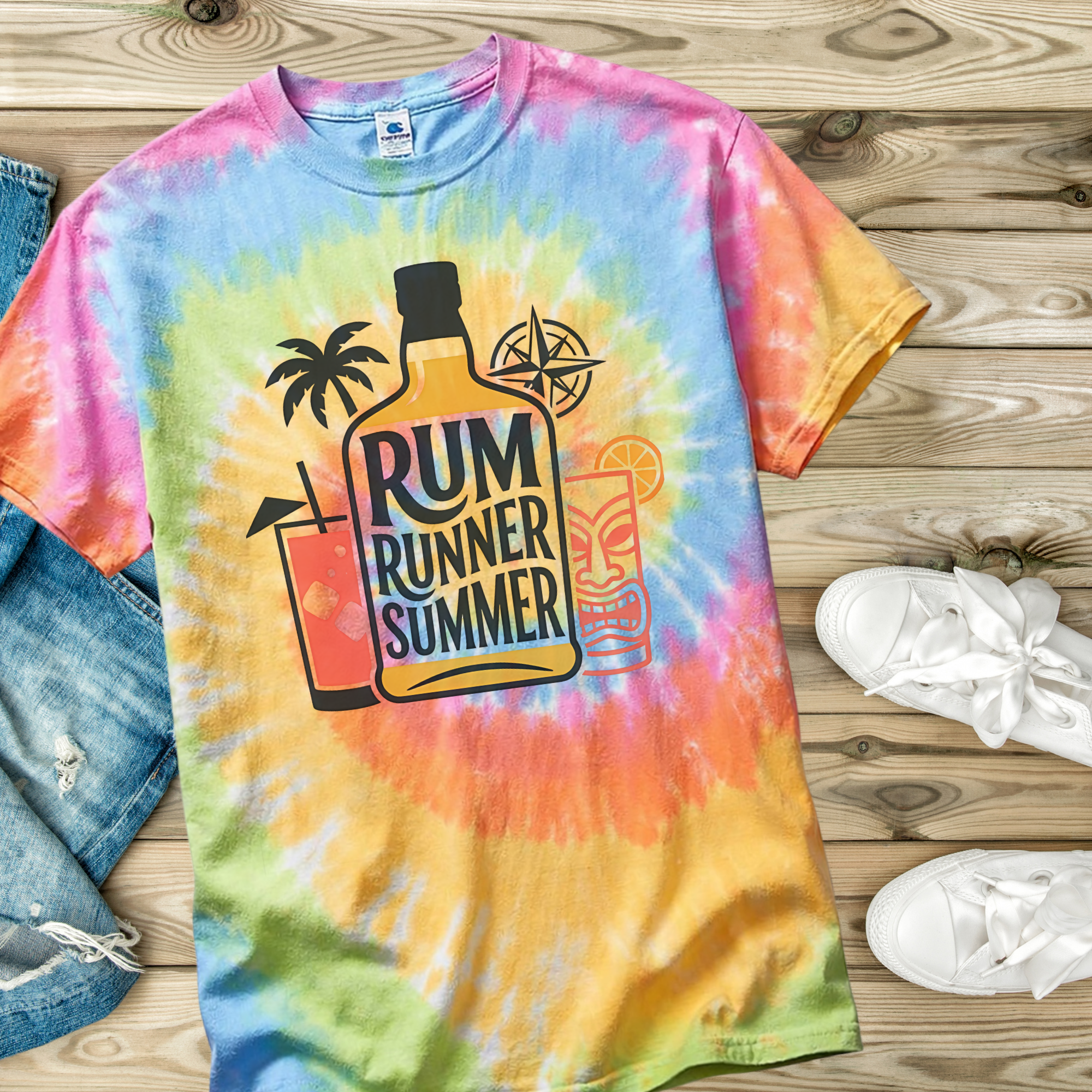 Tie-dye t-shirt with 'Rum Runner Summer' design on a wooden surface with jeans and shoes.
