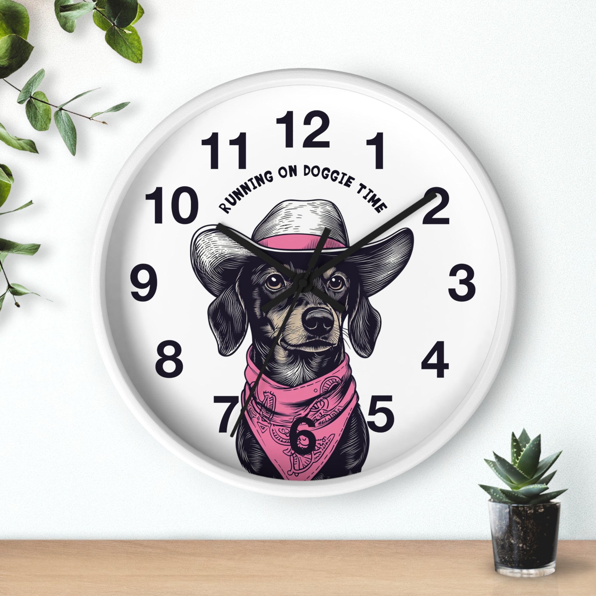 White Wall clock with black hands and a dog illustration and 'Running on Doggie Time' text, surrounded by plants.