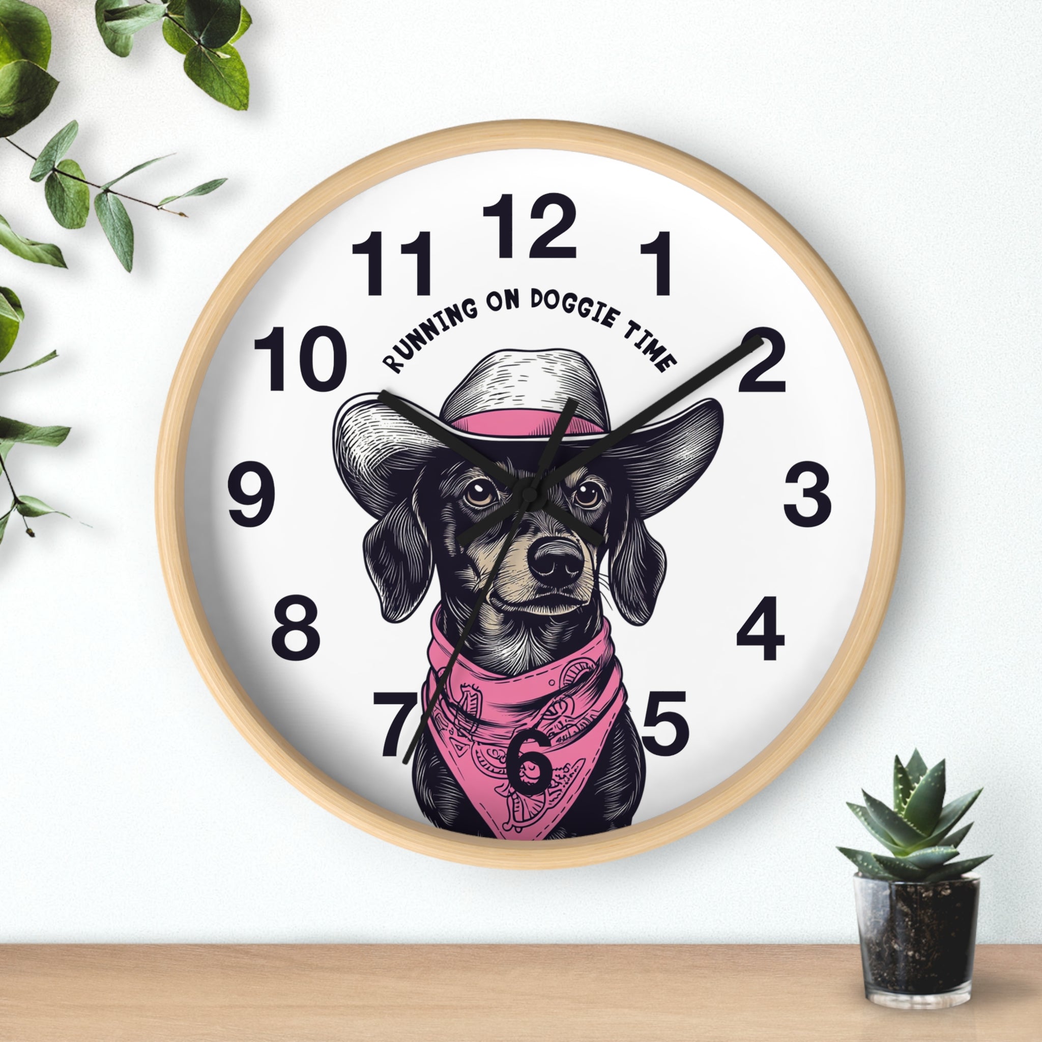Wood wall clock with black hands and a dog illustration and 'Running on Doggie Time' text, placed on a surface with plants.