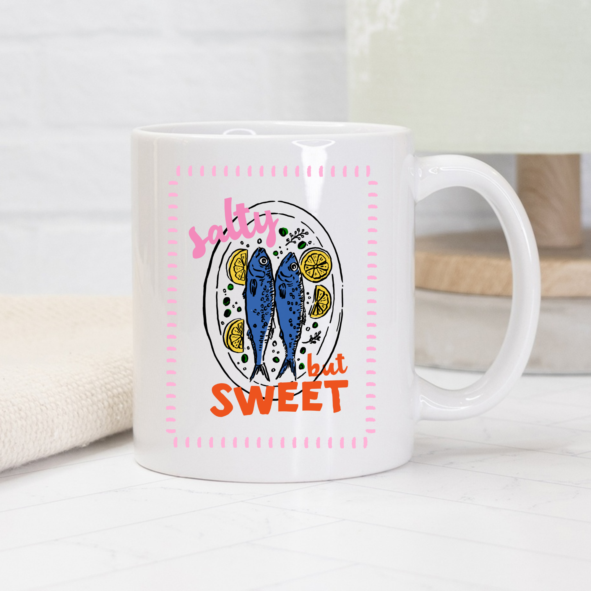 White 11oz. mug with sardine fish and lemon design and text 'salty but sweet' on a light background