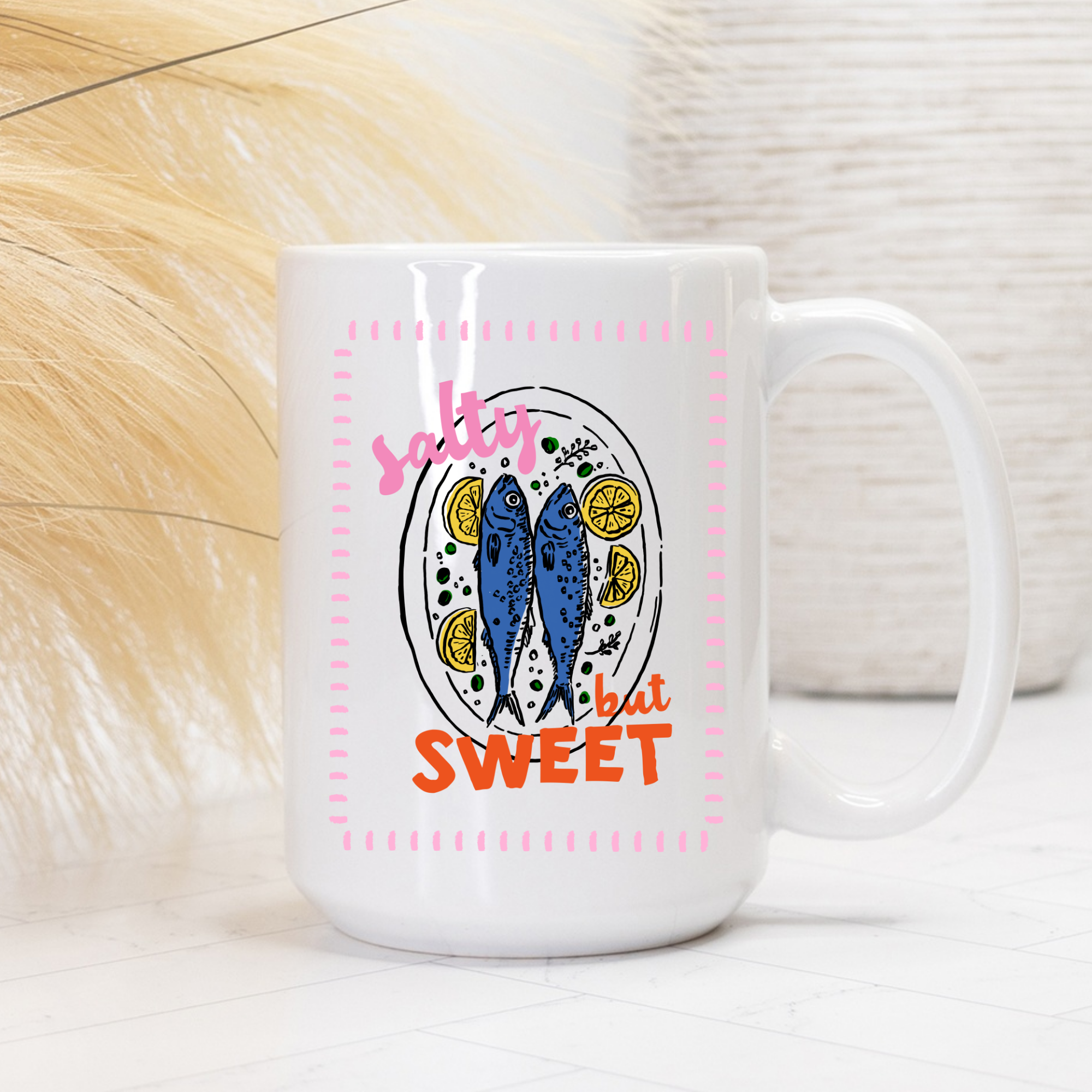 White 15oz. mug with a sardine fish design and text 'salty but sweet' on a neutral background