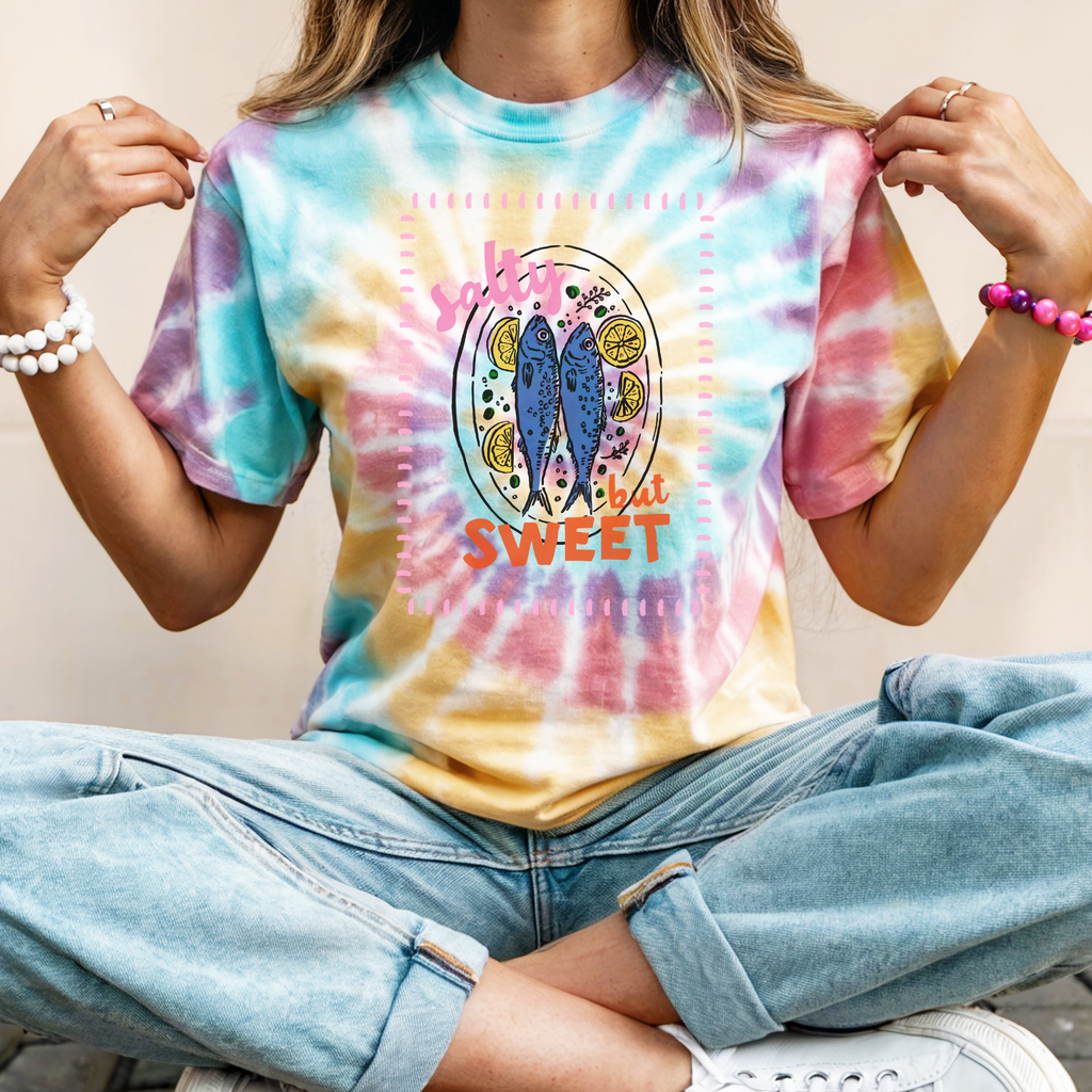 Person wearing a tie-dye t-shirt with a graphic design and text.