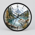 A round wall clock with a black frame and black Roman numerals, featuring a scenic nature print of a mountain lake, evergreen trees, and deer on the face. The clock hands and second hand are black, and it is photographed against a neutral light gray background.