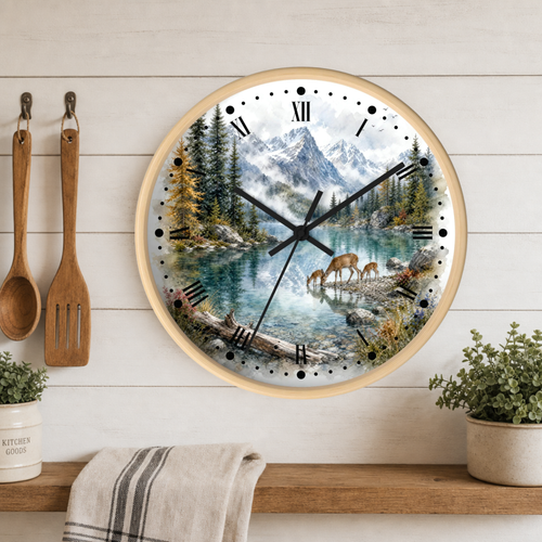 A round wall clock with a light wood frame hangs on a white wood-paneled wall above a shelf. The clock face features a scenic mountain lake landscape with deer, trees, and Roman numerals.