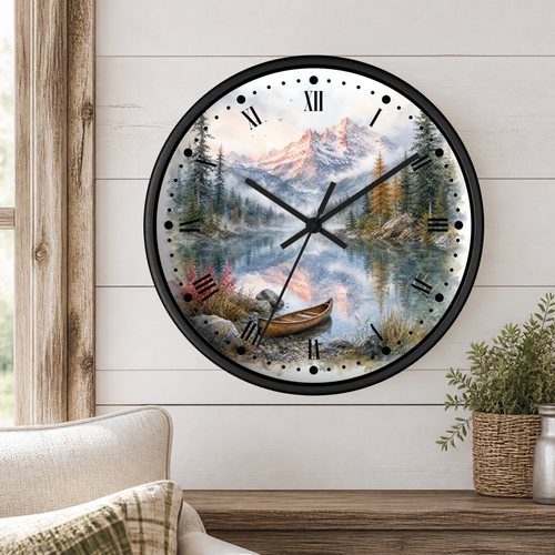 A round wall clock with a scenic mountain lake print and black Roman numerals, mounted on a white wood-paneled wall above a wooden table with a plant and part of a sofa visible.