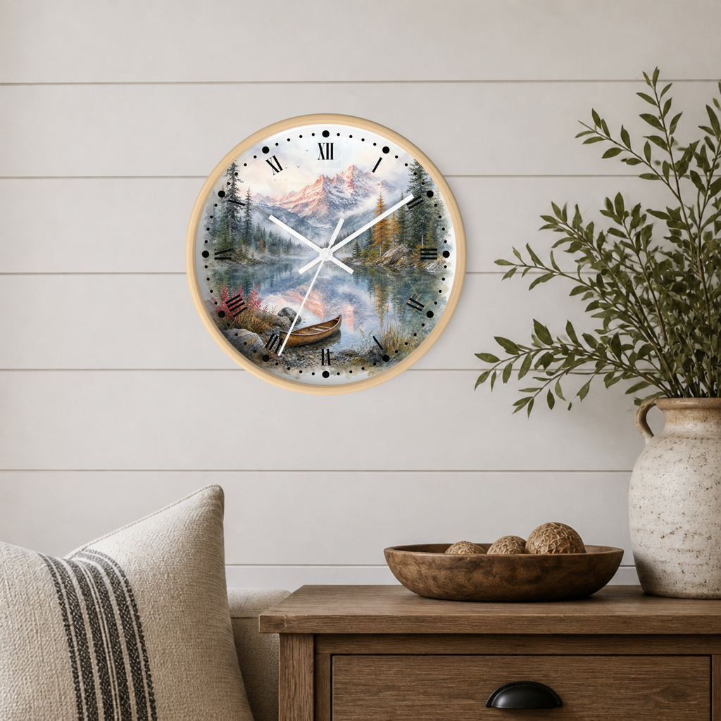 A round wall clock with a light wood frame and a scenic mountain lake print, mounted on a white shiplap wall above a wooden side table with a vase and bowl.